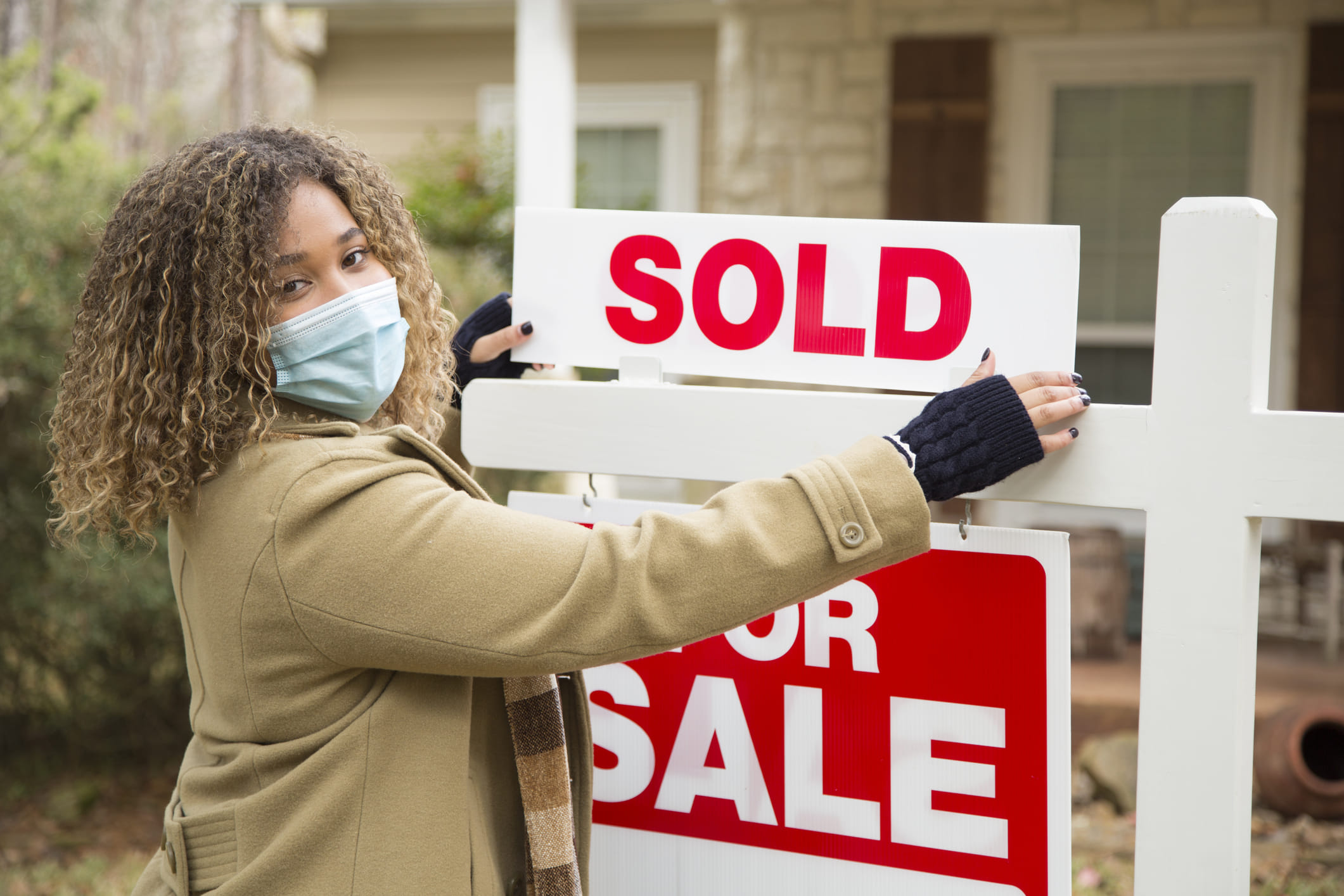 Real Estate Saleswoman placing a sold sign on a For Sale 